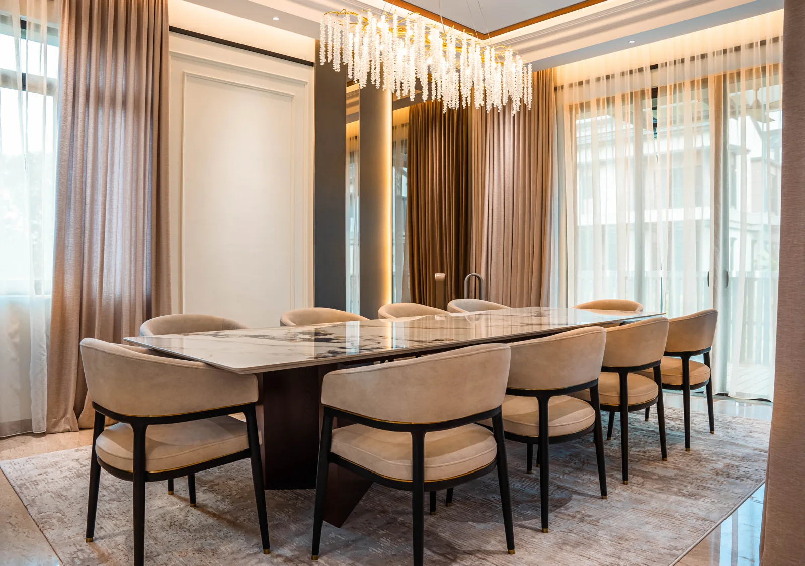 Dining room with a long marble table, upholstered chairs, a crystal chandelier and sheer curtains, Setia Marina One, Cyberjaya, Malaysia, by Blaine Robert Design