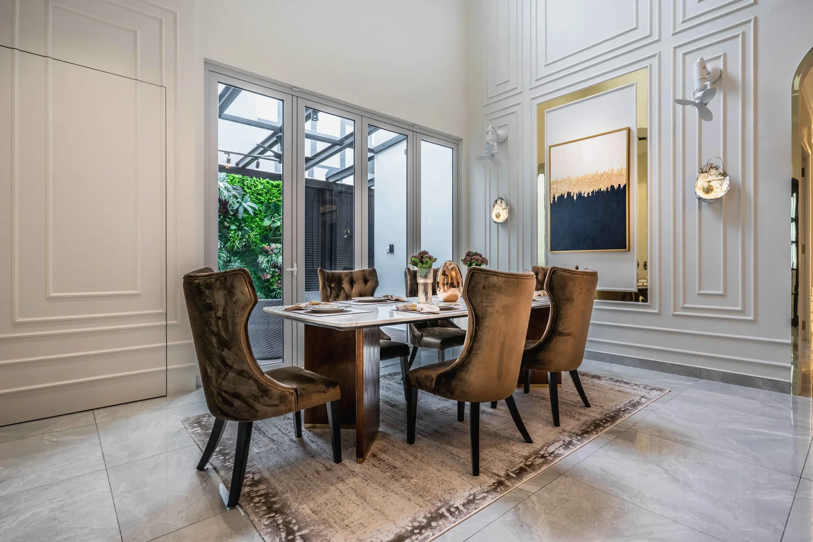 Dining area with velvet chairs, panelled walls and glass doors to a planted side court, EcoSpring Villa, Johor Bahru, Malaysia, by Blaine Robert Design