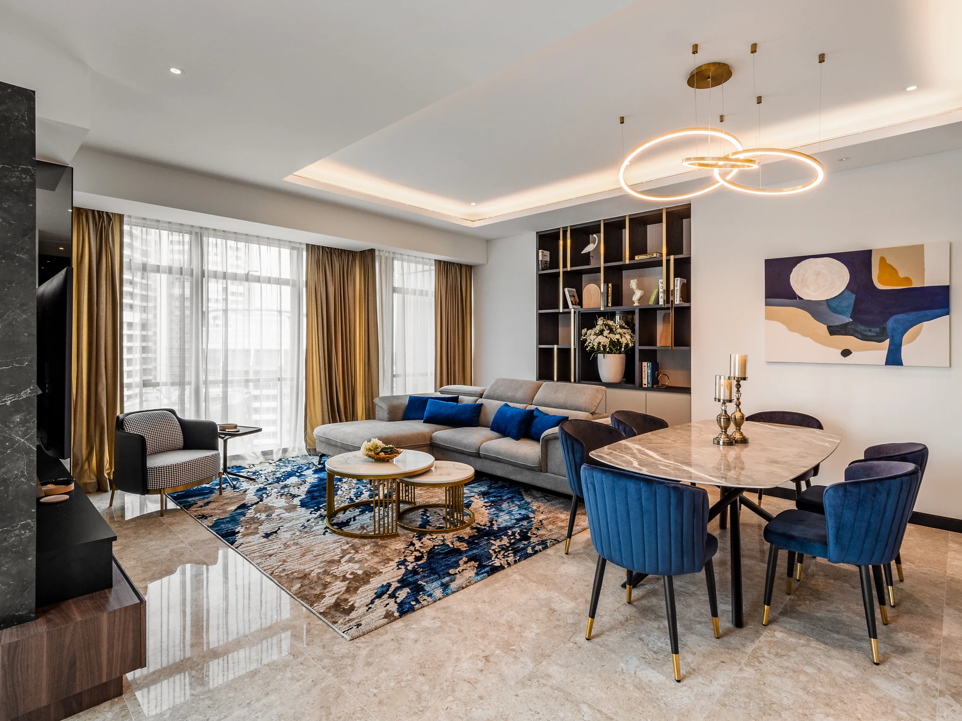 Open-plan living and dining room with an oval stone table, blue velvet chairs and a ring pendant, Ritz-Carlton Residences, Kuala Lumpur, Malaysia, by Blaine Robert Design