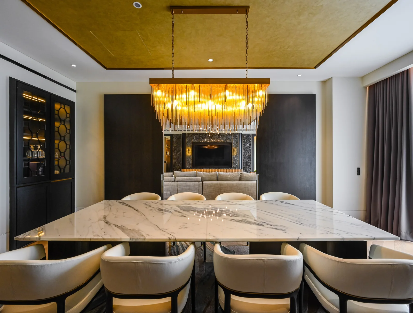 Dining room with a glass-rod chandelier over a marble table and lit glass cabinets, Aira Residence, Kuala Lumpur, Malaysia, by Blaine Robert Design